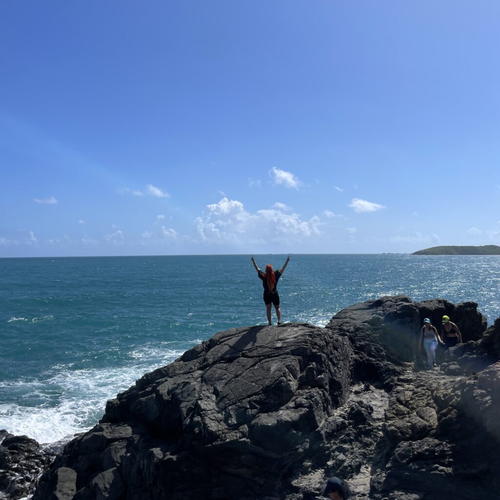 Girl reaching the top clif during Fajardo Puerto Rico hike at Root to Rise Retreat