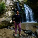 Teresa Prendes-Walls standing by a waterfall in Nagarkot Nepal during a nature hike and retreat activity